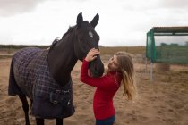 Девочка-подросток гладит лошадь на ранчо — стоковое фото