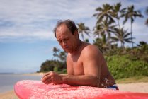 Surfista di sesso maschile che tiene la tavola da surf in spiaggia — Foto stock