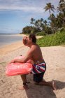Surfeur masculin tenant une planche de surf à la plage — Photo de stock