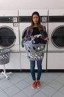 Retrato de la mujer que lleva la cesta de la ropa en la lavandería - foto de stock