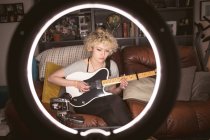 Жіночий блогер грає на гітарі у вітальні вдома — стокове фото