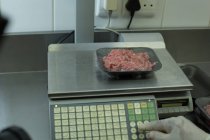 М'ясник перевіряє вагу упакованого м'яса в м'ясному магазині — стокове фото