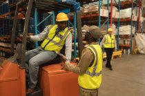 Travailleurs masculins interagissant les uns avec les autres dans l'entrepôt — Photo de stock