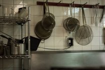 Steel strainer hanging on hook in kitchen at restaurant — Stock Photo