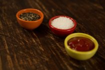 Соус и соль в миске на деревянном столе — стоковое фото