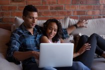 Couple utilisant un ordinateur portable dans le salon à la maison — Photo de stock