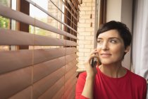 Женщина разговаривает по мобильному телефону в гостиной дома — стоковое фото