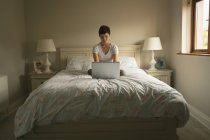 Жінка використовує ноутбук на ліжку в спальні вдома — стокове фото