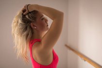Женщина, стоящая с руками на волосах в фитнес-студии — стоковое фото