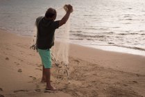 Fischer angelt in der Abenddämmerung am Strand — Stockfoto