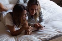 Лесбиянки используют цифровой планшет в спальне дома — стоковое фото
