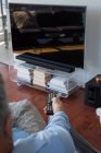 Чоловік змінює канали під час перегляду телевізора у вітальні вдома — стокове фото
