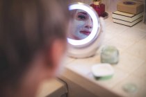 Belle femme regardant dans le miroir à la salle de bain — Photo de stock