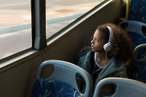 Ragazza adolescente che ascolta musica sulle cuffie mentre viaggia in autobus — Foto stock