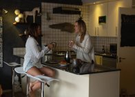 Лесбиянки пьют кофе дома на кухне — стоковое фото