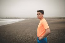 Young man standing on shore at the sea — Stock Photo