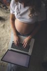 Беременная женщина использует ноутбук в гостиной на дому — стоковое фото