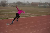 Female athlete running from starting block on the running track — Stock Photo
