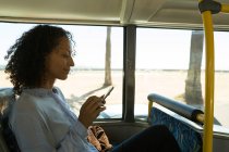 Frau benutzt Handy während Busfahrt — Stockfoto