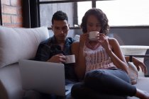 Пара має лимонний чай під час використання ноутбука у вітальні вдома — стокове фото