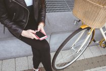 Низкая часть женщины с помощью мобильного телефона на тротуаре — стоковое фото
