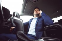 Businessman talking on mobile phone in a modern car — Stock Photo