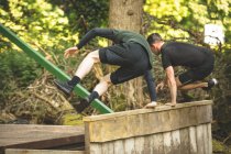 Deux hommes s'entraînent sur un parcours d'obstacles au camp d'entraînement — Photo de stock