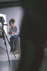 Femme photographe utilisant un téléphone portable dans un studio photo — Photo de stock