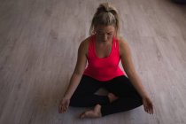 Belle femme effectuant du yoga dans un studio de fitness — Photo de stock