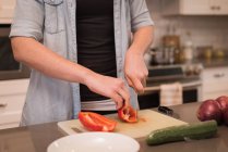 Femme coupant poivron dans la cuisine à la maison — Photo de stock