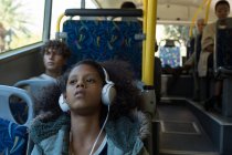 Дівчина-підліток слухає музику на навушниках під час подорожі в автобусі — стокове фото