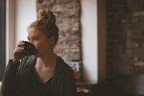 Femme réfléchie prenant un café au café — Photo de stock