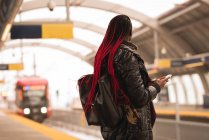 Stylish woman using mobile phone at railway platform — Stock Photo