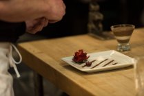 Чоловічий шеф-кухар, який подає фрукти на тарілці на кухні — стокове фото