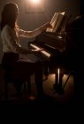 Vista laterale della studentessa che suona il pianoforte nella scuola di musica — Foto stock