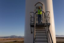 Ingeniero de pie en la entrada de un molino de viento en un parque eólico - foto de stock