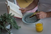 Mann liest ein Buch beim Frühstück zu Hause — Stockfoto