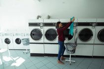 Giovane donna controllando i suoi vestiti a lavanderia — Foto stock