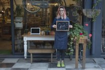Баріста стоячи з відкритим Вивіска зовні кафе — стокове фото