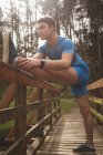 Junger Mann streckt sich auf Holzbrücke im Wald — Stockfoto