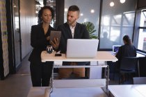 Бизнес-руководители обсуждают за планшетом во время работы над ноутбуком в офисе — стоковое фото
