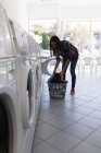 Junge Frau wäscht im Waschsalon — Stockfoto