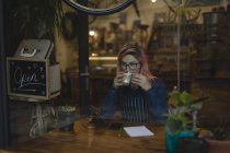 Молода жінка п'є каву в кав'ярні — стокове фото