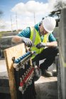 Travailleur de la construction examinant les tuyaux sur place — Photo de stock