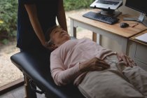 Крупный план физиотерапевта, делающего массаж головы пожилой женщине — стоковое фото