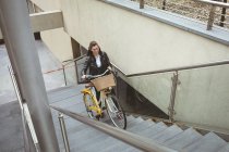 Belle femme avec vélo montant les escaliers — Photo de stock