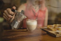 Junge Frau gießt Kaffee aus einem Wasserkocher — Stockfoto