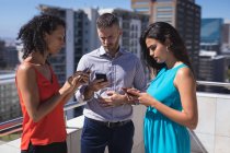 Führungskräfte nutzen Smartphone an einem sonnigen Tag auf der Büroterrasse — Stockfoto