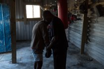 Trainer training young male boxer at fitness studio — Stock Photo