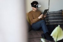 Man in virtual reality headset using digital tablet in living room at home — Stock Photo